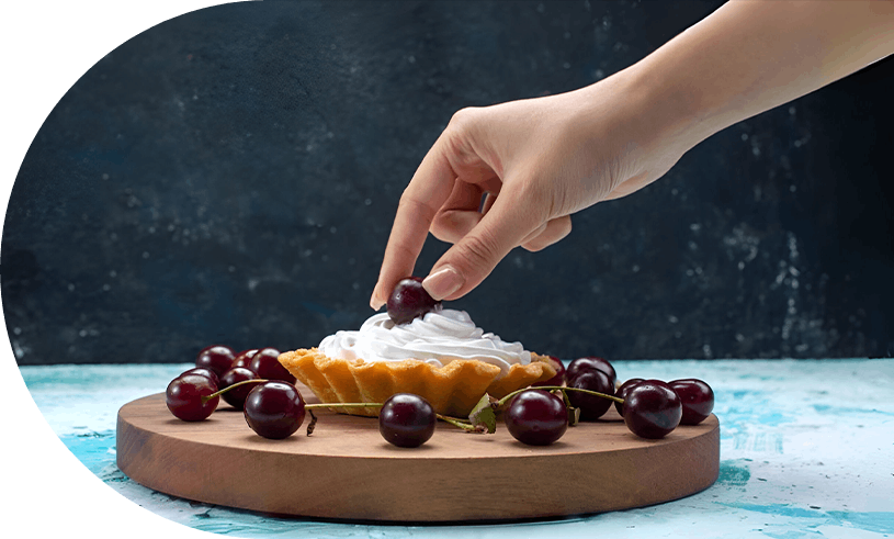 Las manos del panadero colocan delicadamente bayas sobre un pastel.